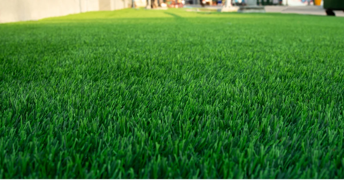 Close-up view of vibrant green artificial grass on a wide, flat surface in an outdoor area.